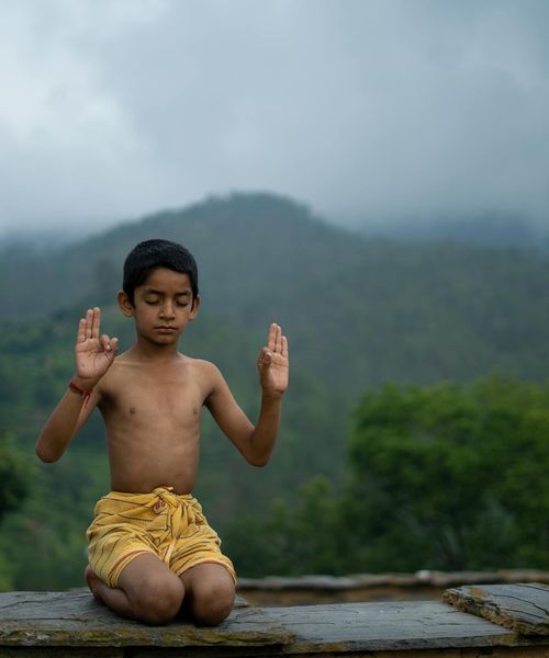 Person meditating peacefully outdoors with a serene natural background.